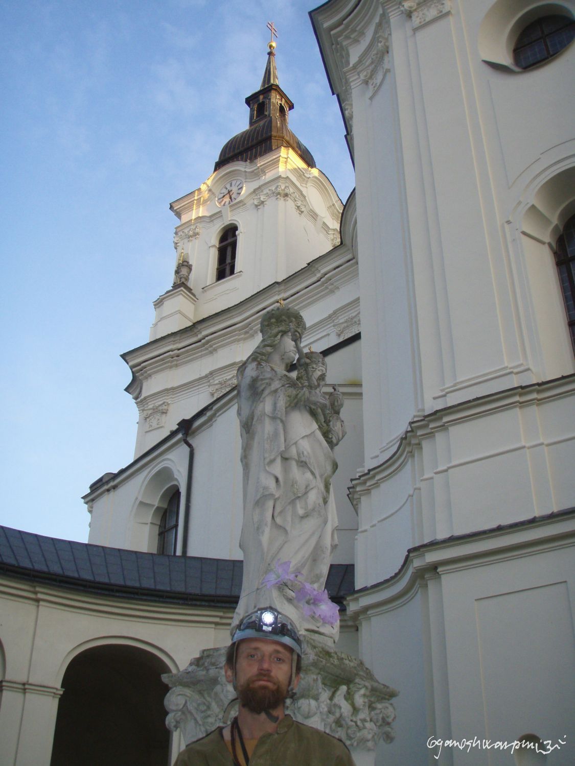 Křtinský Schliemann pod sochou Panny Marie a věží  chrámu Panny Marie ve Křtinách.  Foto: Marek Gyaneshwarpuri, samospoušť 2008.